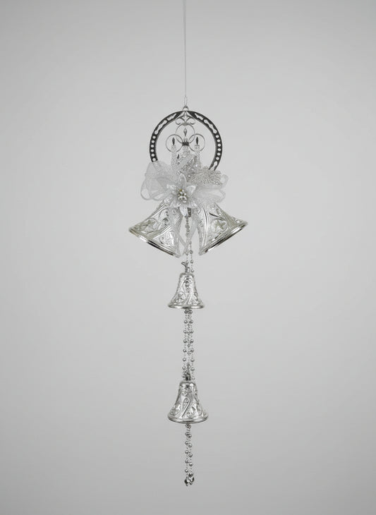 Decorative silver bell hanging ornament on a wooden surface with a colorful background.