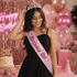 Woman wearing a Birthday Girl sash at a birthday party with balloons, cake and celebration decor.