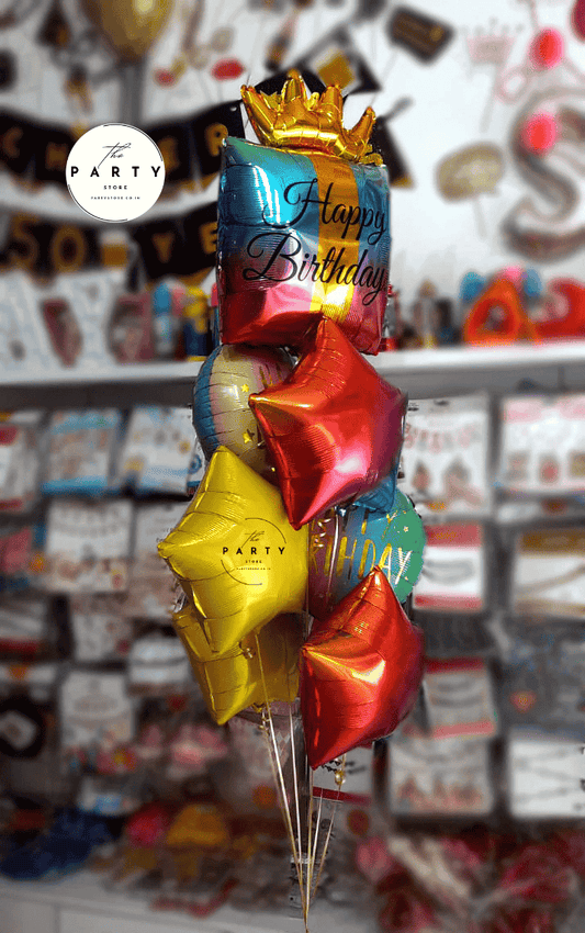 A festive set of 7 helium foil balloons for a birthday celebration, including a large crown-shaped balloon and coordinating “Happy Birthday” text balloons in metallic colors, perfect for party decoration
